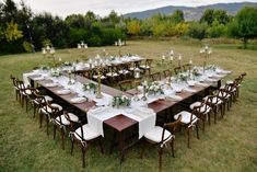 a long table set up with white and green centerpieces for an outdoor dinner