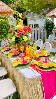 a table set up with plates, flowers and straws for a tropical themed party