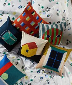 four colorful pillows sitting on top of a bed