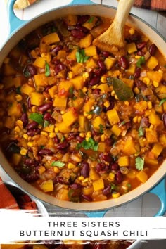 three sisters butternut squash chili in a blue pot with a wooden spoon on the side