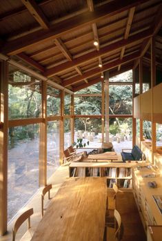 the inside of a house with wooden tables and chairs in front of large glass windows