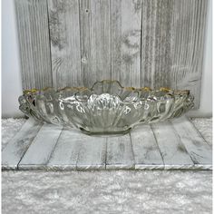 a large glass bowl sitting on top of a wooden table next to a white wall