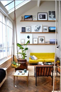 a living room filled with lots of furniture and pictures on the wall above it's windows