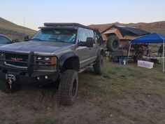 a truck parked in the middle of a field with tents and other vehicles around it