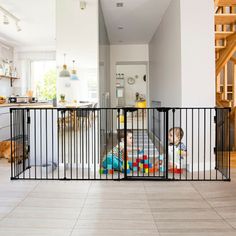 two toddlers are playing in their playpen at the bottom of stairs that lead up to an open floor plan