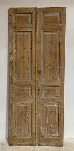 an old pair of wooden doors sitting on top of a white floor next to a wall