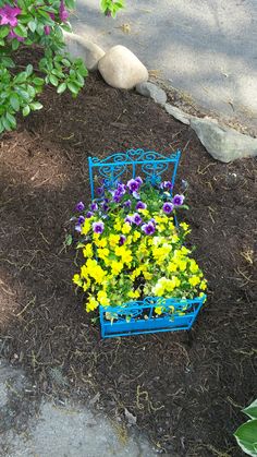 a blue bench with flowers in it on the ground