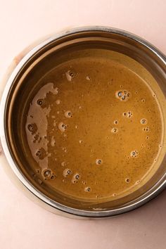 a metal bowl filled with brown liquid on top of a pink tablecloth covered floor