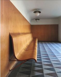 a wooden bench sitting in the middle of a room with checkered floor and walls