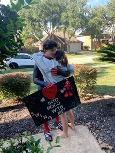 two children hugging each other in front of a sign