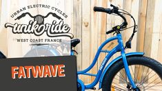 a blue bike parked next to a wooden fence with the words fatwave on it