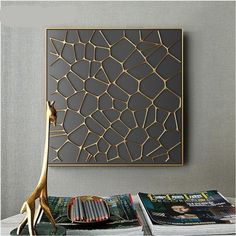 a table topped with books and magazines next to a wall mounted art piece on the wall