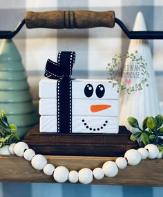 a snowman gift box sitting on top of a wooden shelf next to other christmas decorations