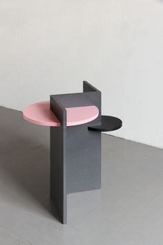 a grey and pink table sitting on top of a white floor next to a wall