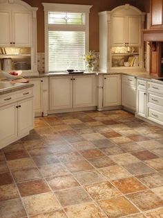 a kitchen filled with lots of white cabinets and counter top space next to a window