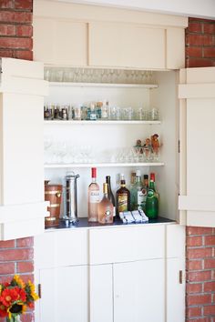 the shelves are filled with liquor bottles and glasses on top of each other in front of a brick wall