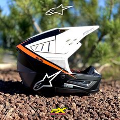 a helmet sitting on top of a pile of dirt next to some trees and rocks