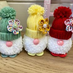 three knitted santa claus hats with pom - poms on them sitting next to each other