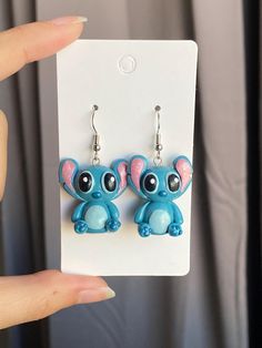 a pair of blue and pink earrings with an elephant on it's earring