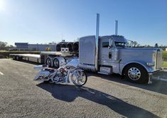 a large semi truck parked next to a motorcycle on the side of the road in front of a trailer