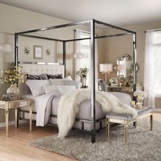 a bedroom with a four poster bed and white fur rugs on the hardwood floor