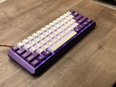 a purple and white keyboard sitting on top of a wooden table