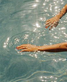 a woman swimming in the water with her hand extended out to touch the water's surface