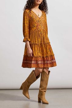 Take a stylish lead on your day-to-day agenda with this printed peasant dress made from knit crepe fabric. We can't get enough of the flowy fit, tiered body finished with ruffled seams, pop-over v-neck featuring non-functional buttons, 36" length, and three-quarter sleeves with elastic cuffs that add a fancy flourish at the edge. Pop-over v-neck Flowy fit 36" long Three-quarter sleeve with elastic cuff, non-functional buttons with elastic loops, border print Knit crepe 95% Polyester 5% Spandex M Casual Boho Dress In Rayon For Fall, Bohemian Rayon Dress With Ruffle Hem, Bohemian Patterned Daywear Dresses, Bohemian Patterned Dresses For Daywear, Bohemian Patterned Day Dresses, Printed Viscose Midi Dress For Daywear, Fall Tiered Midi Dress For Daytime, Viscose Dresses For Daywear In Fall, Fall Boho Print Dress