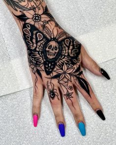 a woman's hand with black and white tattoos on her left hand, holding a skull in the middle