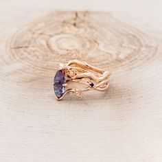 a gold ring with an amethorate stone in the center on a wooden surface