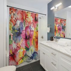 a bathroom with floral shower curtain next to a white toilet and sink in front of a mirror