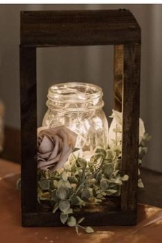 a mason jar filled with flowers sitting on top of a wooden table next to a candle