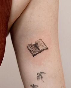 a woman's arm with a book and butterflies tattoo on her left side ribcage