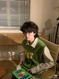 a young man sitting in a chair holding a book