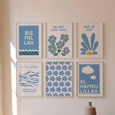 four blue and white posters hanging on the wall above a table with a vase in front of it