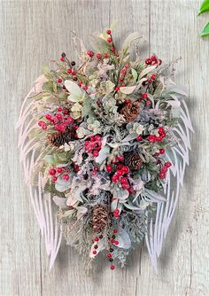 a bouquet of red berries and greenery on a white wooden surface with leaves, twigs and pine cones