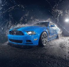 a blue mustang is splashing water on the ground