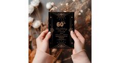 a woman holding up a black and gold 60th birthday card