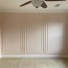 an empty room with a ceiling fan and beige paneled walls in the corner area