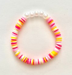 a pink, yellow and white beaded bracelet with pearls on it's end