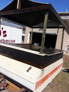 an old boat sitting in front of a building with a sign that says bob's barbecue