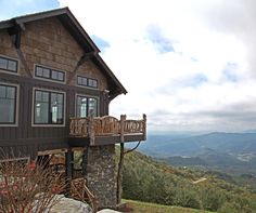 a house on top of a hill with mountains in the background