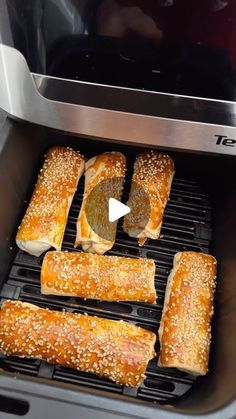 bread rolls being cooked in an air fryer with the lid open to show sesame seeds