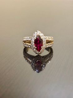 "DeKara Designs Collection Metal- 18K Yellow Gold, .750. Stones- Marquise Ruby Center Beautiful Red Color 1.07 Carats. 16 Round Diamonds F-G Color VS2 Clarity, 1.15 Carats. This is a halo setting with a magnificent marquise ruby set in the center surrounded by 48 round diamonds in a \"U\" pave setting, and features a split shank. The marquise ruby is 1.07 carat with an beautiful hue of red in color. Rubies are the rarest of fine gemstone! The side stones are all F-G in color and VS2-SI1 in clari Luxury Wedding Birthstone Ring With Center Stone, Luxury Wedding Birthstone Ring With Diamond Accents, Luxury Ruby Birthstone Ring For Wedding, Luxury Cubic Zirconia Birthstone Wedding Ring, Luxury 14k Gold Ruby Wedding Ring, Marquise Cluster Ring With Accent Stones For Wedding, Ruby Rings With Marquise Cut In Halo Setting, Ruby Rings With Halo Setting And Marquise Cut, Gold Marquise Gemstone Wedding Jewelry