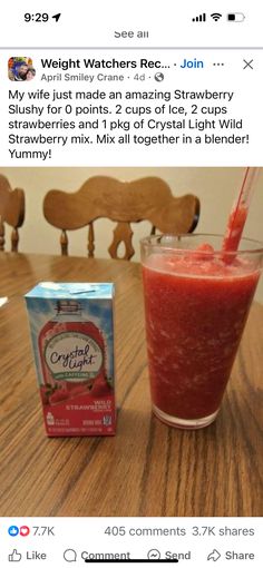 a glass filled with red liquid sitting on top of a wooden table next to a box of gummy