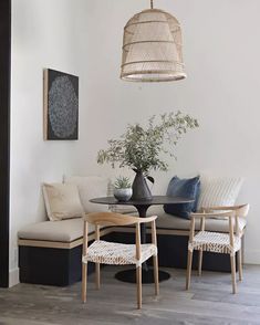 a dining room table with chairs and a bench in front of the wall that is painted white