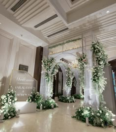 an indoor wedding venue with white flowers and greenery at the entrance to the room