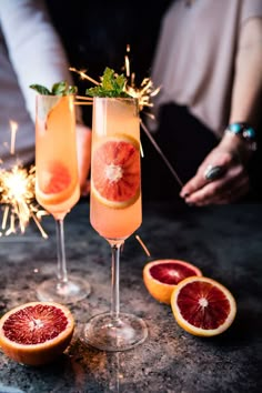 two wine glasses filled with pink grapefruit and garnished with sparklers