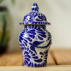 a blue and white vase sitting on top of a wooden table next to a potted plant