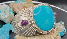 "Kingman turquoise bracelet, purple Sugilite accents, handmade sterling gift jewelry. Large old stock blue Kingman turquoise accented with purple Sugilite. Set in a solid sterling bracelet with sterling wings.  Handmade gift jewelry. Southwest style turquoise bracelet for her. Size: 6.75 Inside:5,25\". Gap: 1.50\". Weight: 59 grams. Kingman turquoise: 31x33mm. 2 Sugilite: 7x10mm. Made by Marvin Boone." Southwestern Polished Cuff Bracelet As Gift, Southwestern Cuff Bracelet With Natural Stones As Gift, Southwestern Natural Stones Cuff Bracelet Gift, Purple Southwestern Jewelry For Gifts, Southwestern Style Purple Jewelry For Gift, Purple Southwestern Jewelry For Gift, Purple Southwestern Style Jewelry For Gift, Turquoise Bracelet With Polished Finish As Gift, Turquoise Bracelets With Polished Finish As A Gift